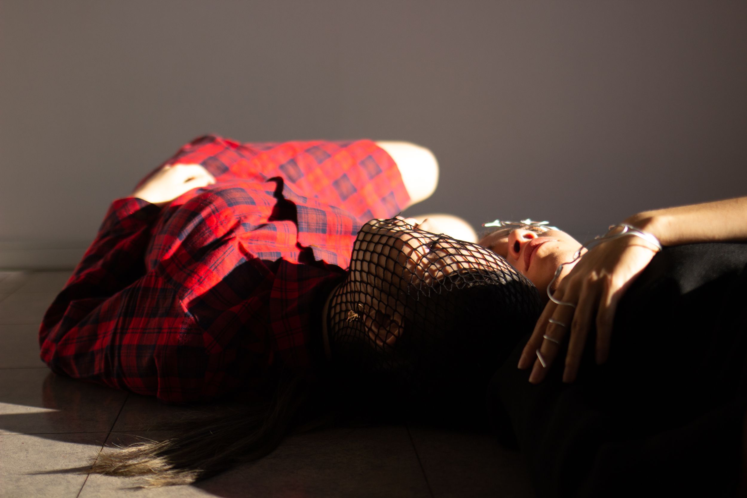 Artistic photograph of figure in red plaid dress lying in dramatic lighting.