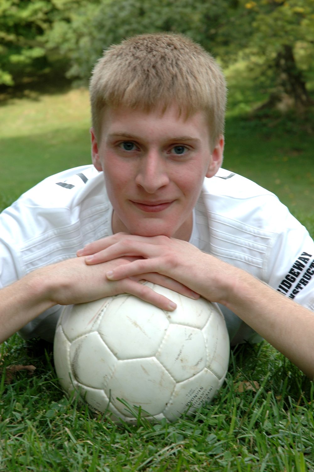 high school senior boy with soccer ball in field