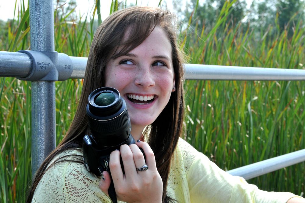 high school senior girl with camera laughing