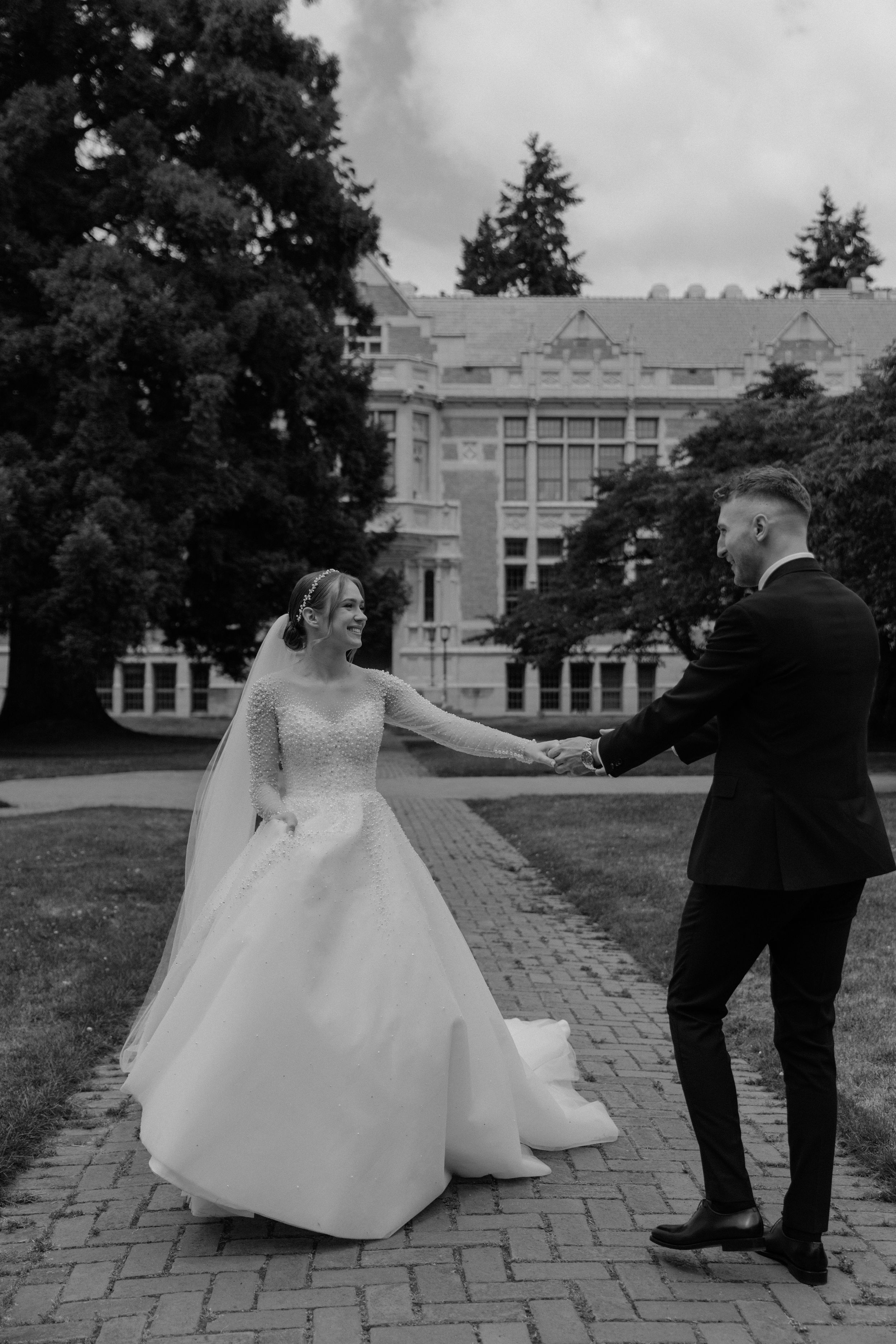A romantic wedding dance moment on a brick pathway in front of a stately brick building.