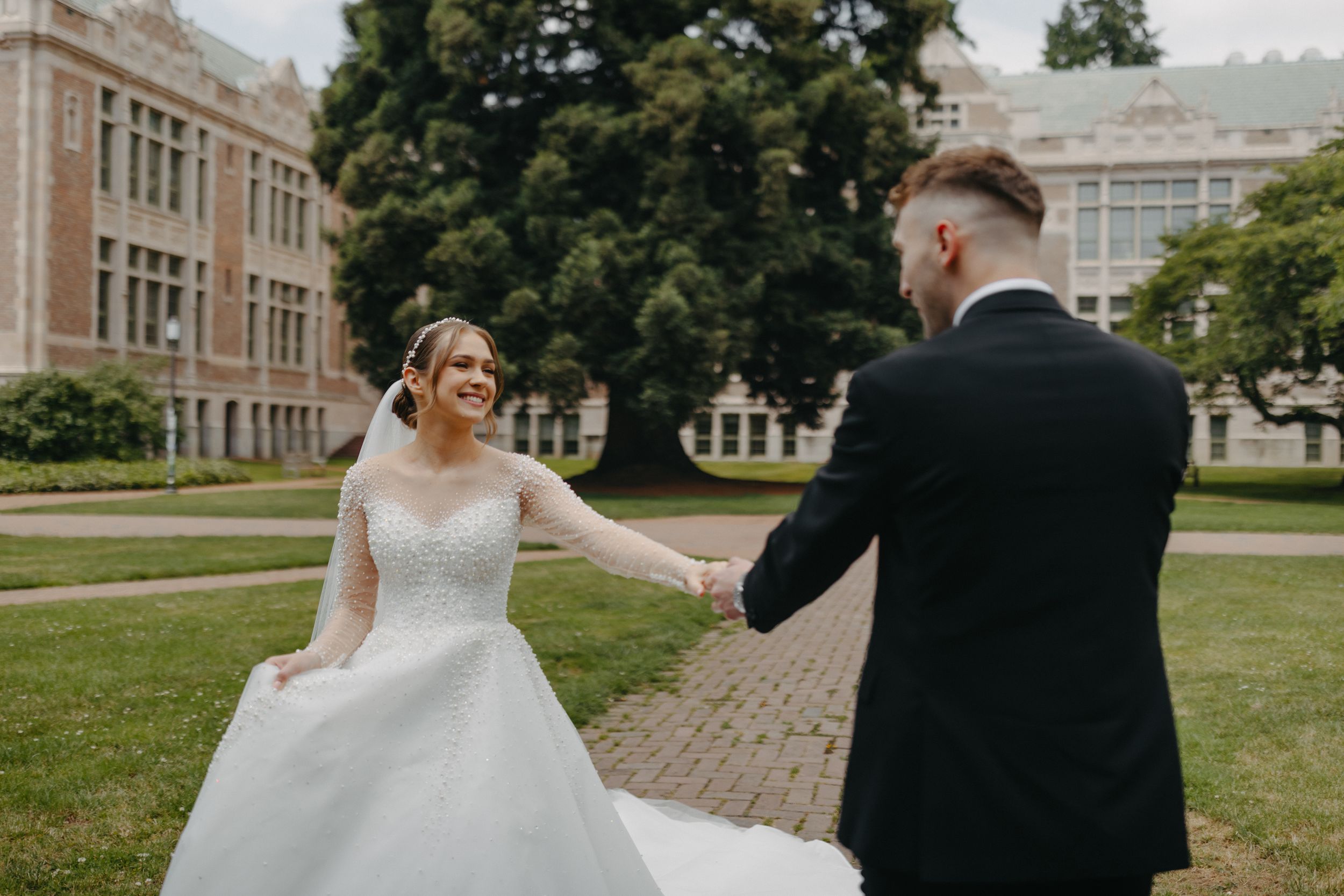 Playful moment between newlyweds dancing on brick pathway in front of historic building.