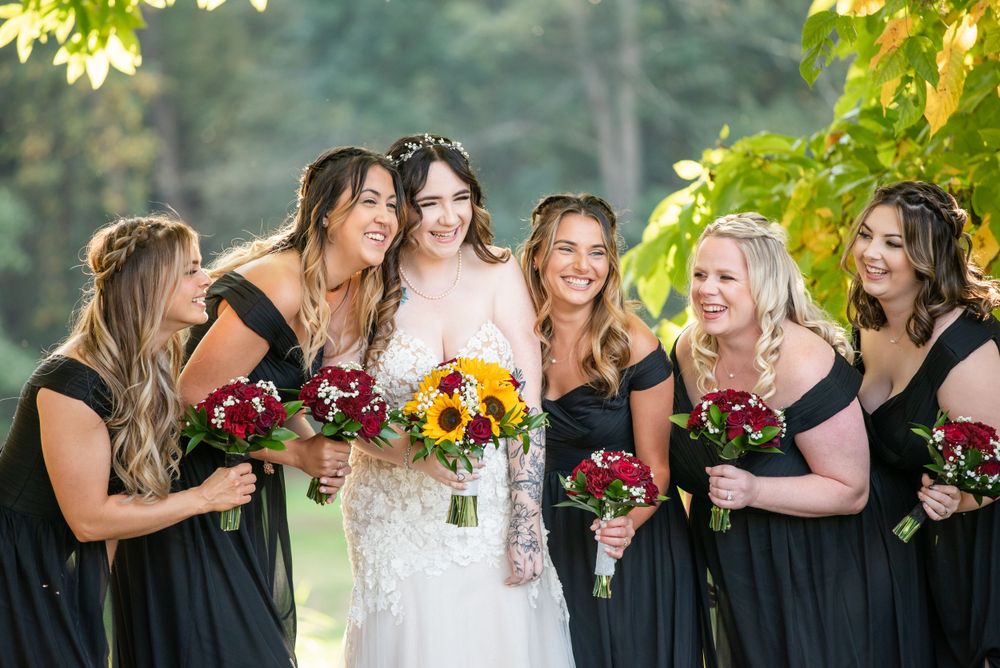 Wedding party holding vibrant bouquets outdoors on sunny day.