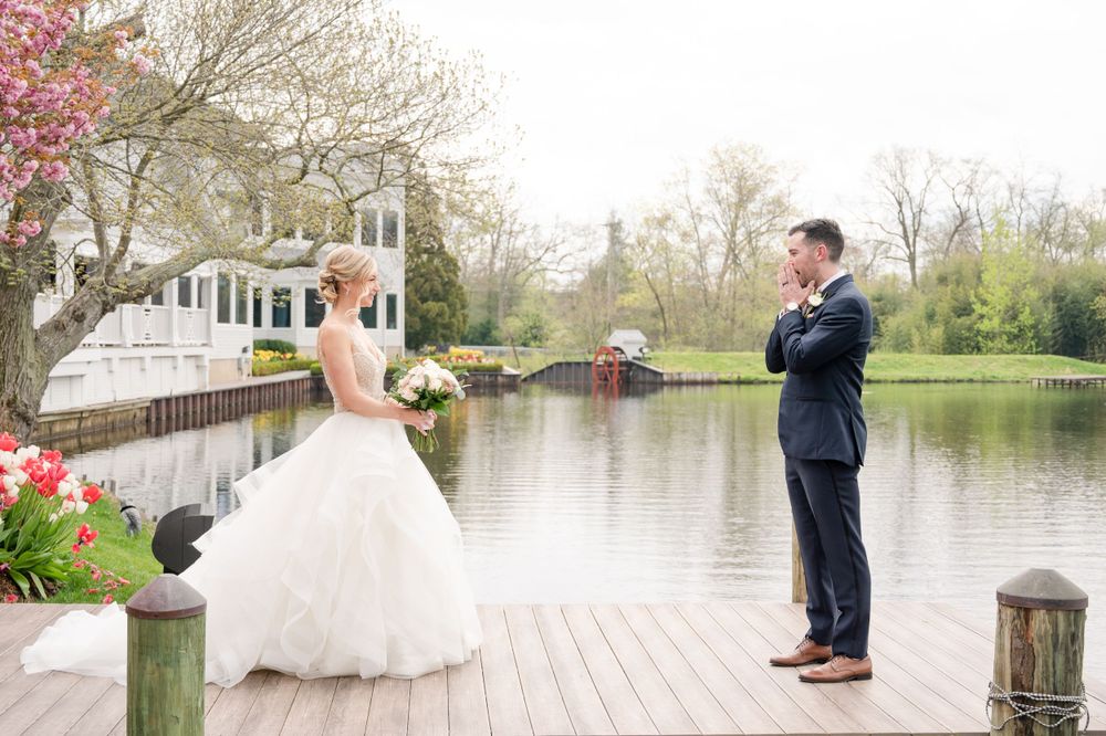 Wedding couple poses on wooden dock by tranquil lake during springtime.