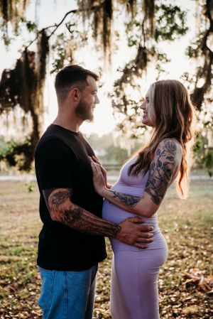 Couple in casual wear sharing intimate moment under Spanish moss trees.