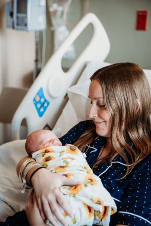 Hospital room scene with mother and newborn wrapped in sunflower print blanket.