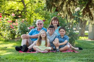 Multi-generational group relaxes together on grass in a blooming garden setting.