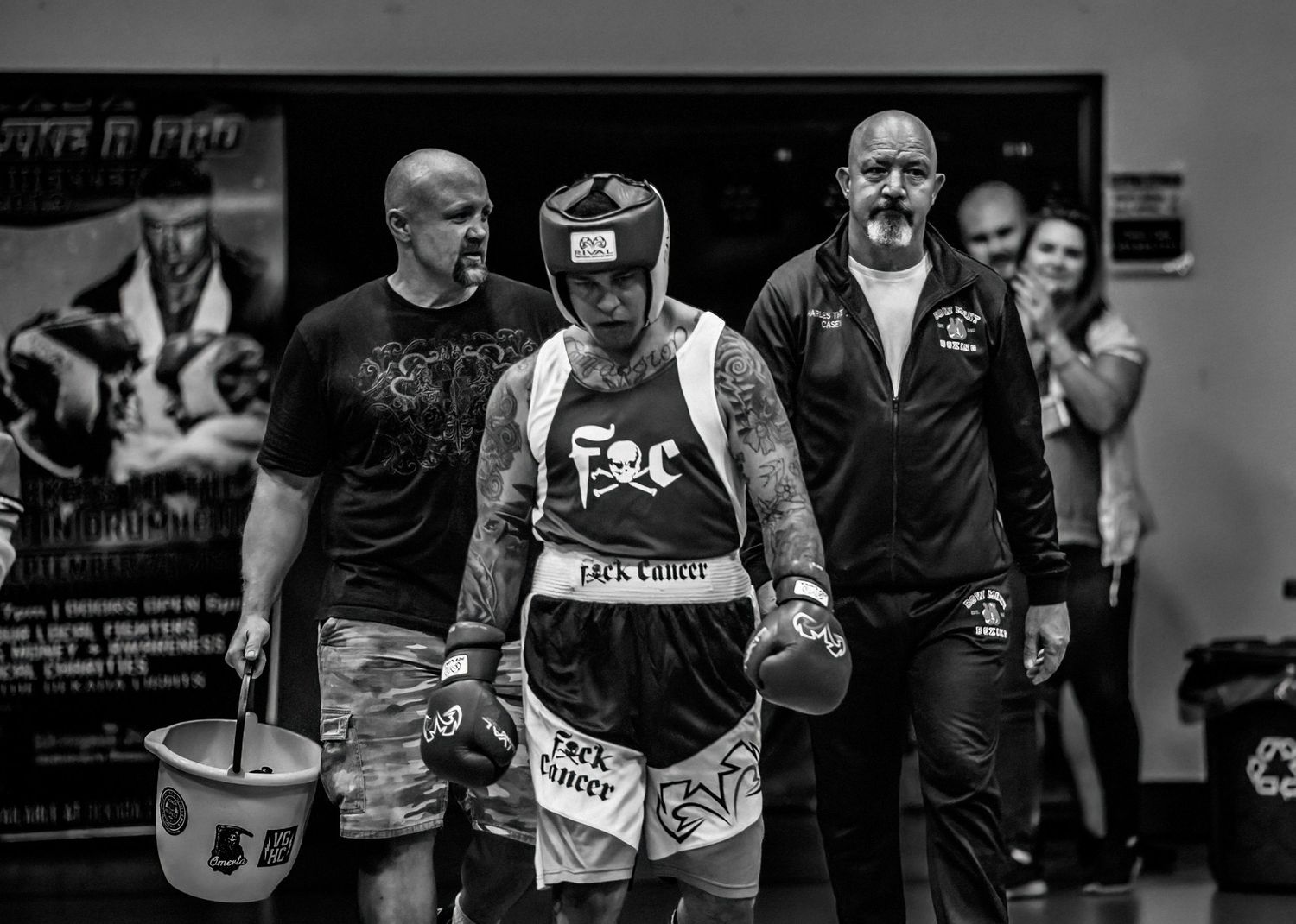 Black and white photo of boxer with entourage entering ring for competition.