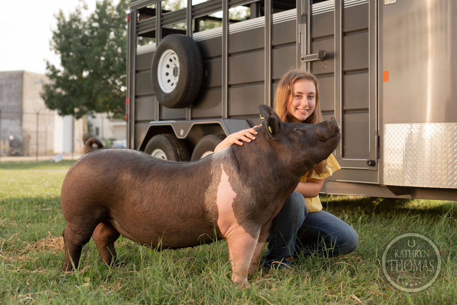 A champion show pig receives attention next to a brown livestock trailer.