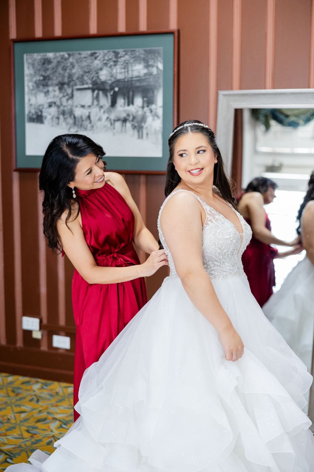 A joyful scene of wedding preparation with attendant helping with the bridal gown.