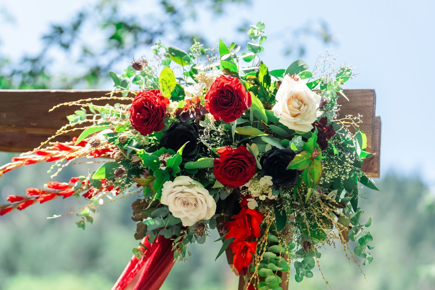 burgundy, black, and white floral arrangement on the arch