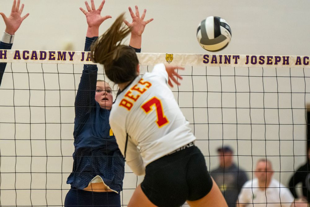 Volleyball players jump at the net during an intense match point. Brecksville Lady Bees, Ohio
