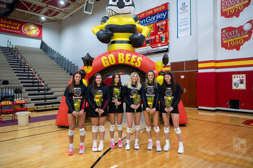 High school volleyball team poses in matching uniforms in front of an inflatable mascot in a gymnasium.  Brecksville Lady Bees, Ohio