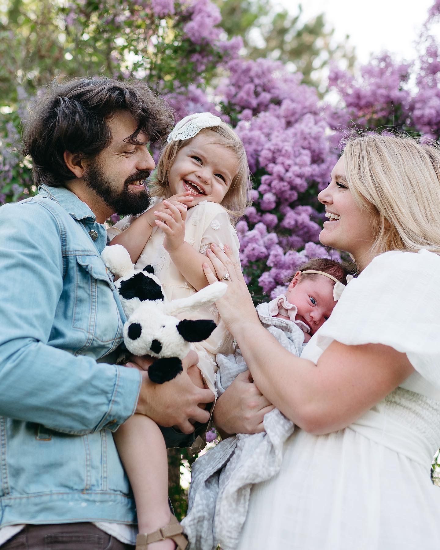 Photographer Katie Griff Photo enjoys time spent with her family amidst the lilac blooms in a spring family photoshoot.