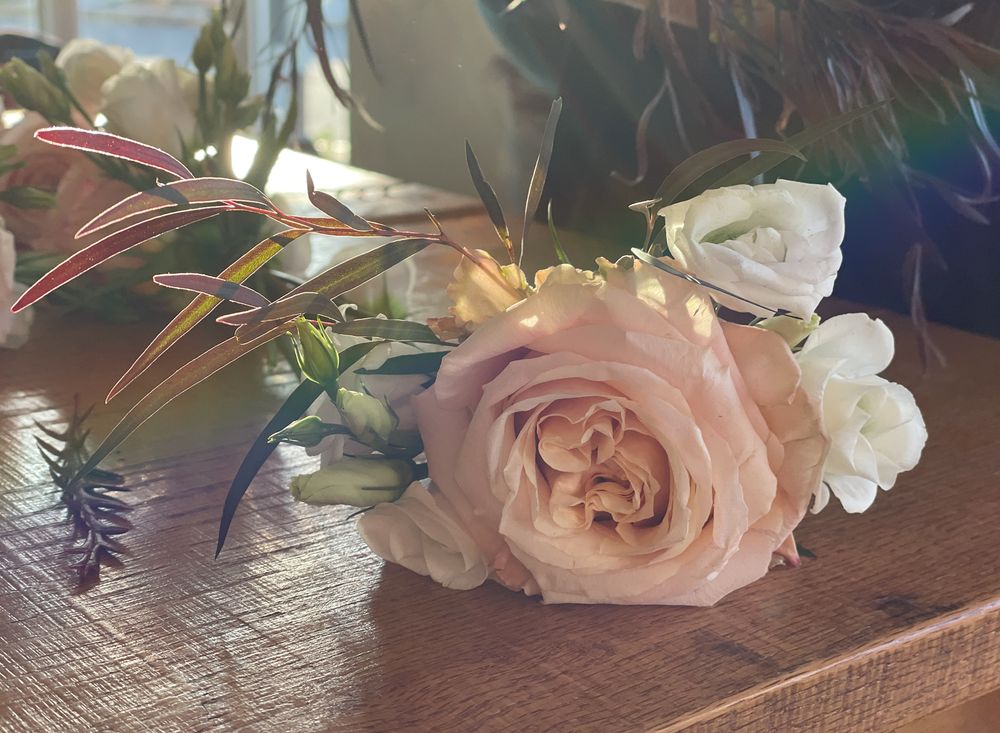 Delicate pink roses with greenery arranged on wooden surface.