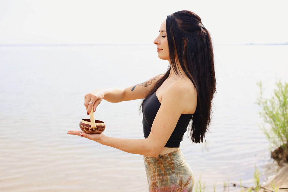 Person in black top holds small dish while posing by waterfront.