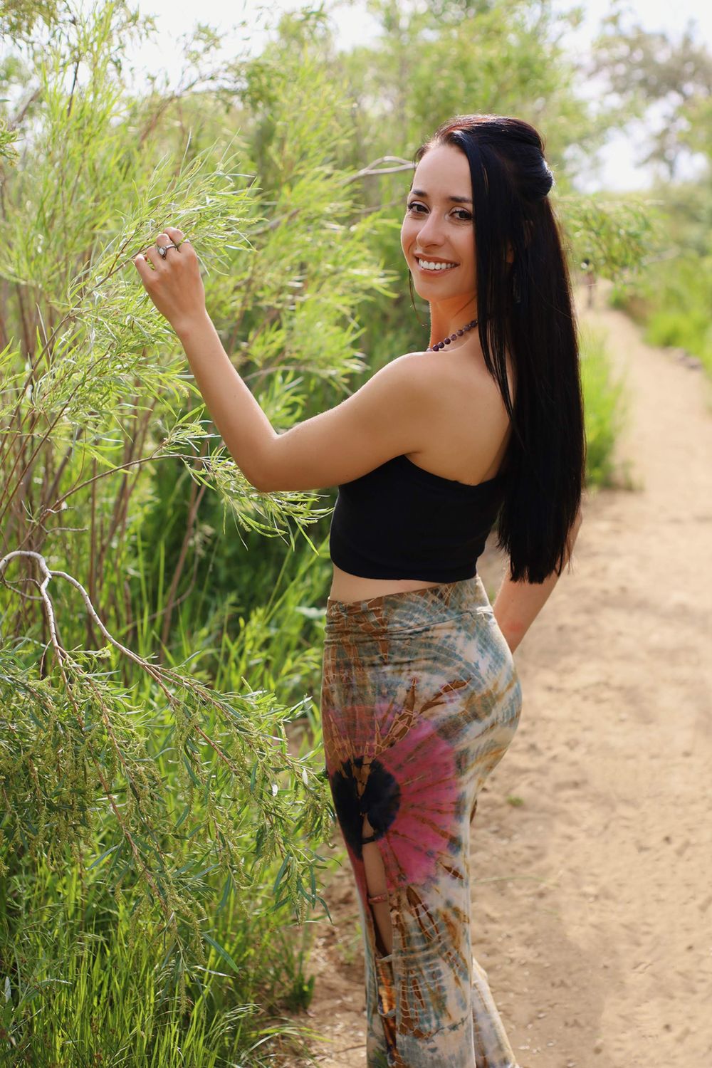 Nature photoshoot featuring a tie-dye maxi skirt and black crop top along a dirt trail surrounded by greenery.