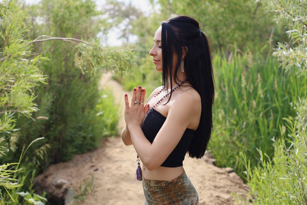 Person in athletic wear stands on nature path surrounded by green vegetation.