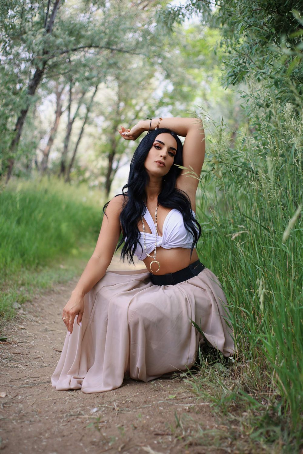 Artistic dance pose on a nature path with flowing skirt and crop top ensemble.