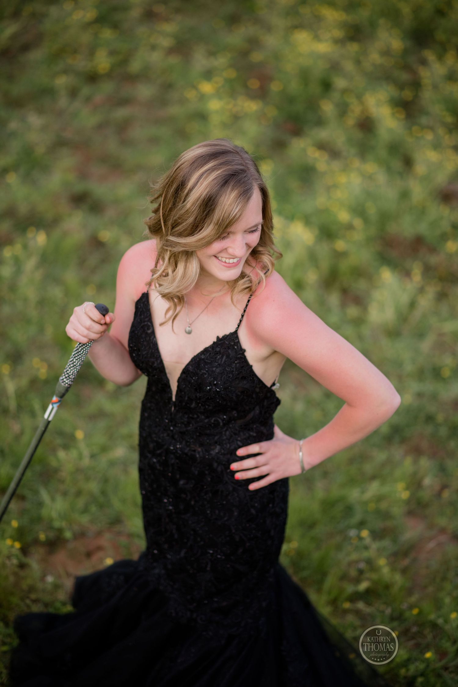 An elegant pose in a black sequined formal dress outdoors among spring foliage.