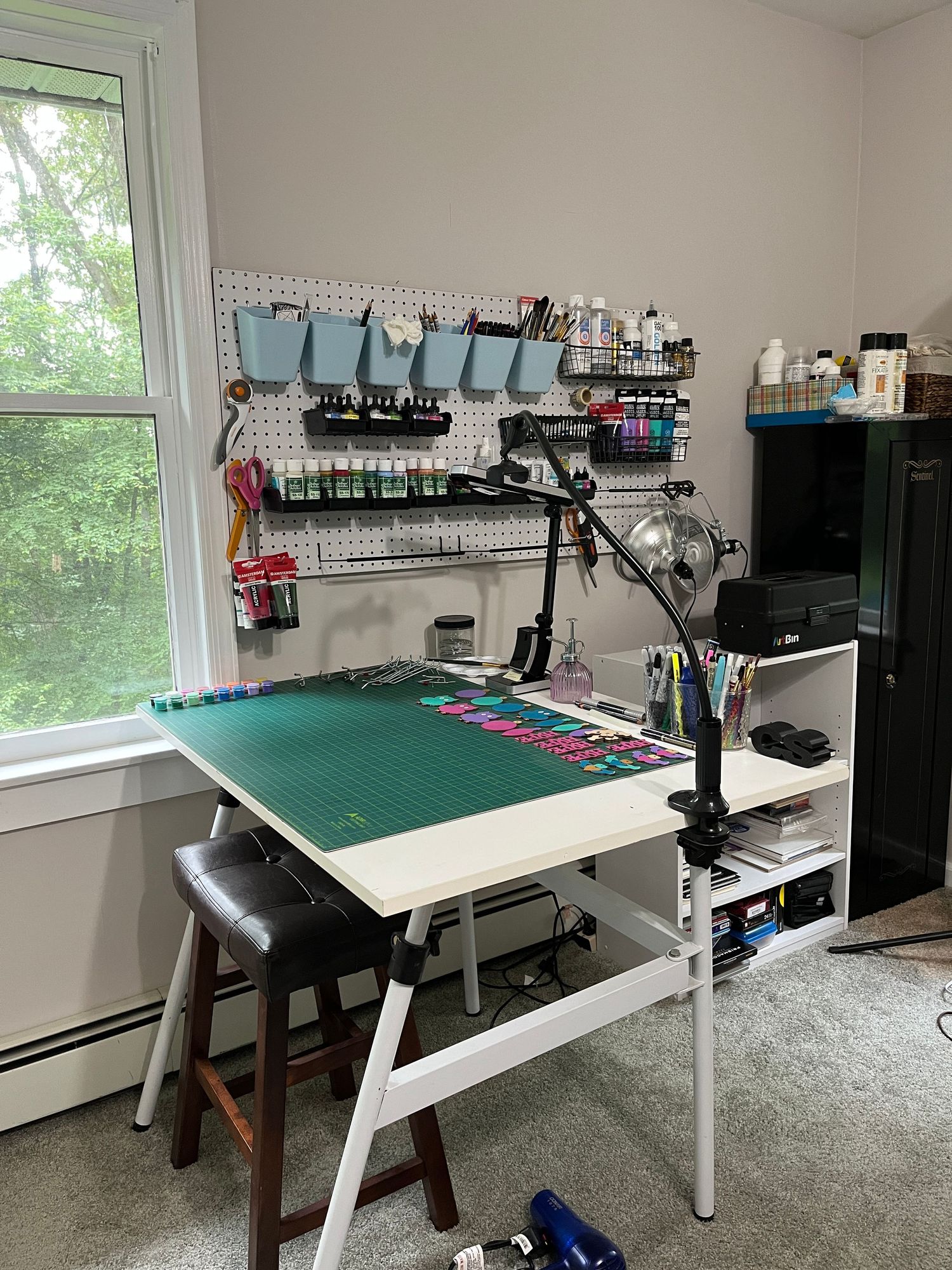 Photo of organized art studio table with supplies on a pegboard.