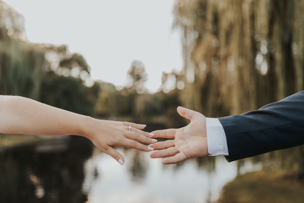 Close-up of hands reaching out to touch in front of a blurred nature background.