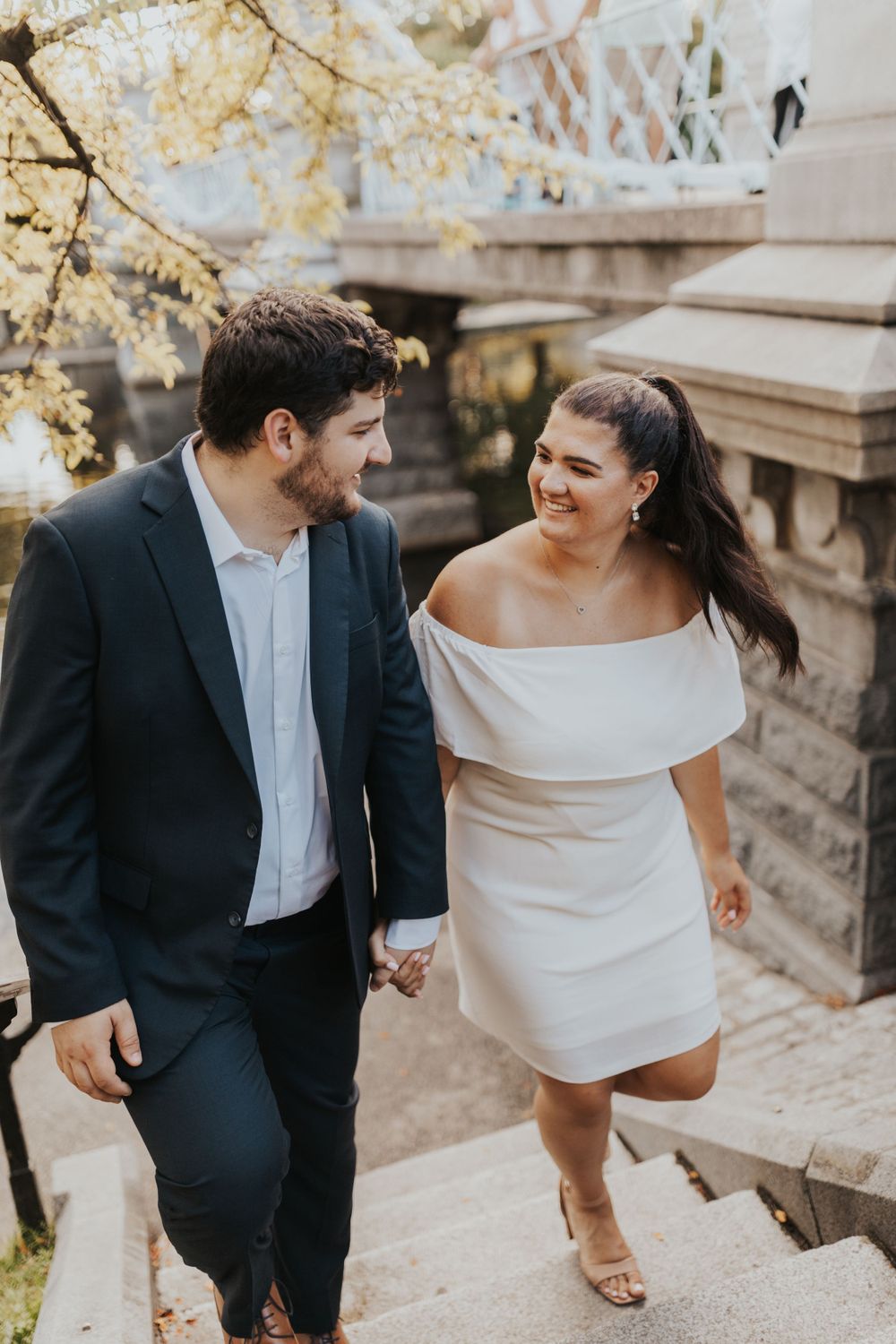 A couple descends stone steps while holding hands and sharing a joyful moment.