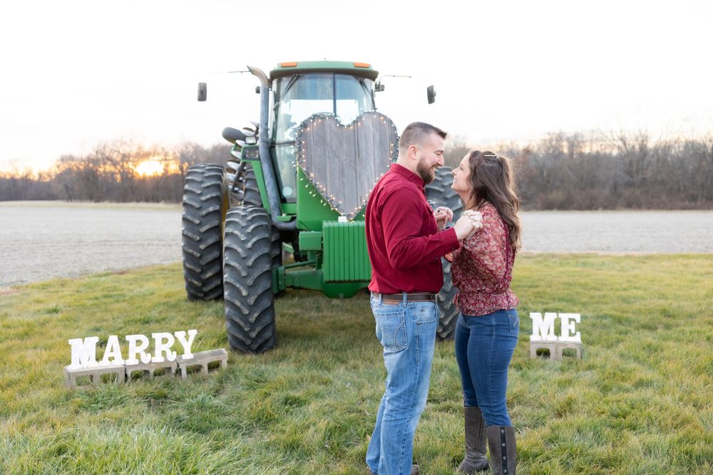 A romantic proposal moment in front of a green tractor during golden hour.