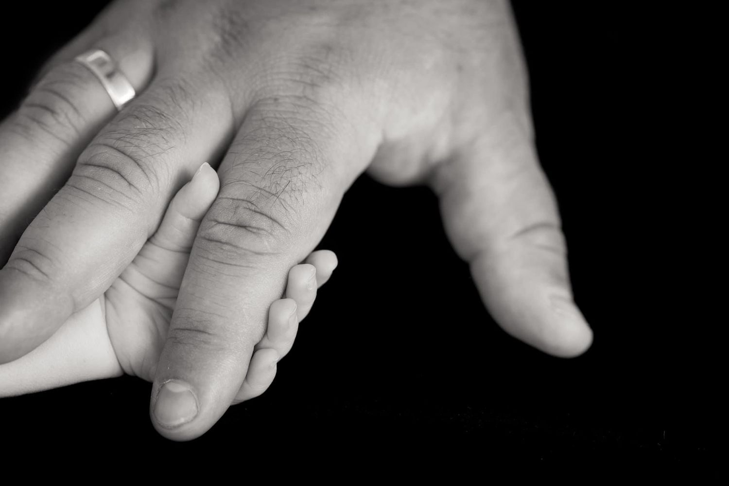 Close-up black and white photo of gentle hands touching.