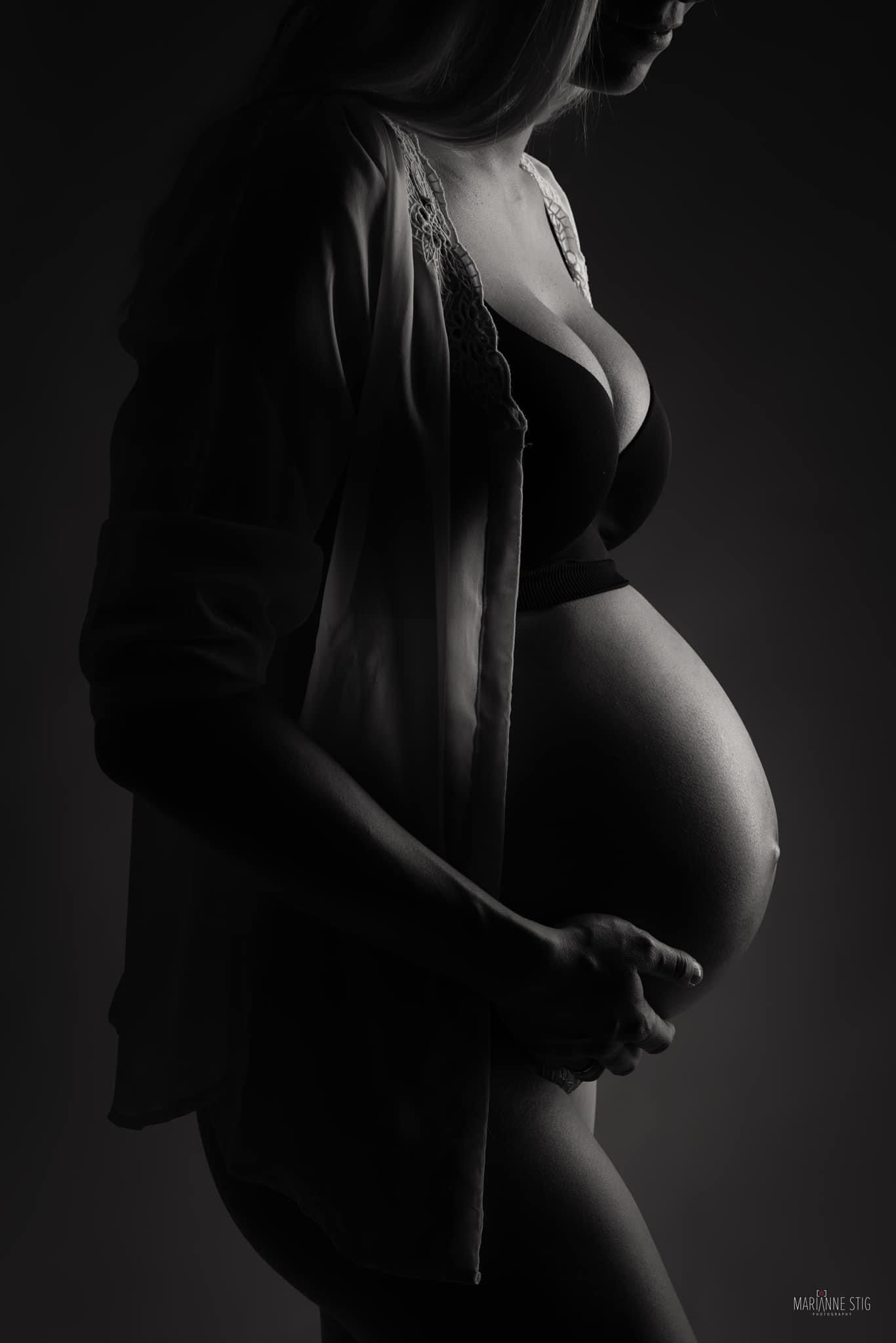 Artistic black and white maternity photo series showing silhouette of pregnant woman against dark background.