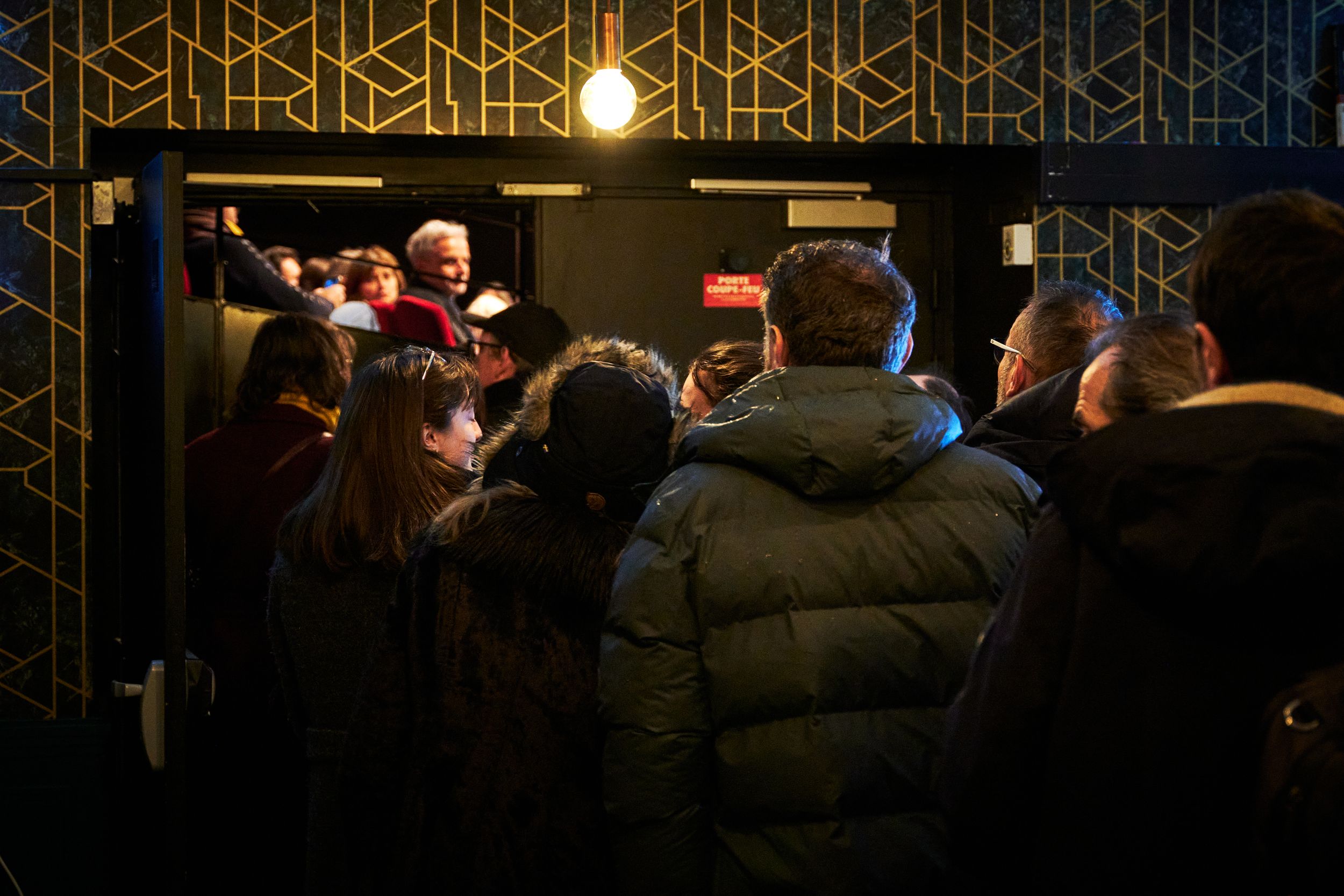 Crowded nightclub entrance with geometric gold pattern lighting.