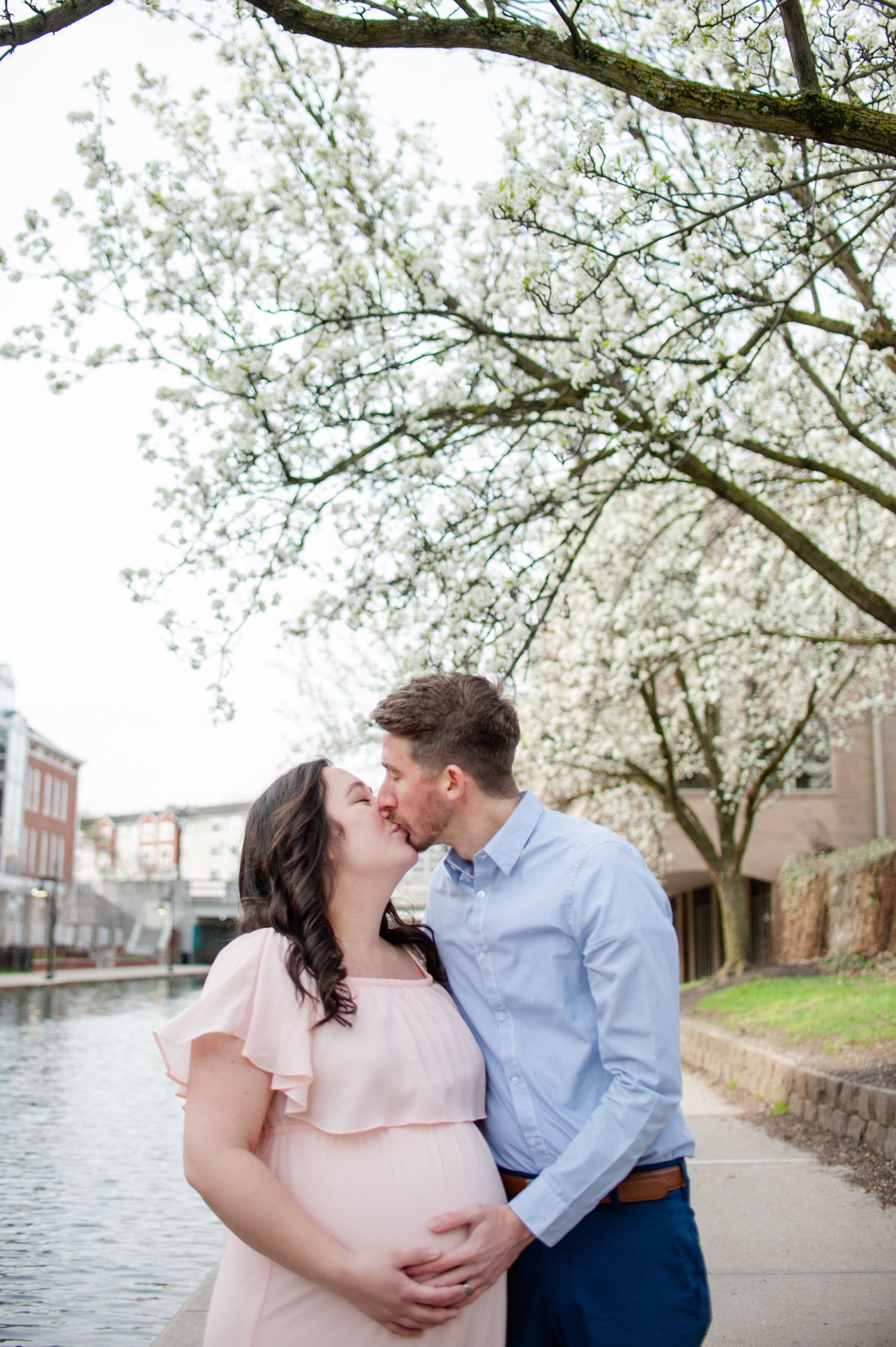 INDIANAPOLIS MATERNITY PHOTOGRAPHER, EXPECTING PARENTS KISS ON DOWNTOWN CANAL, INDIANA