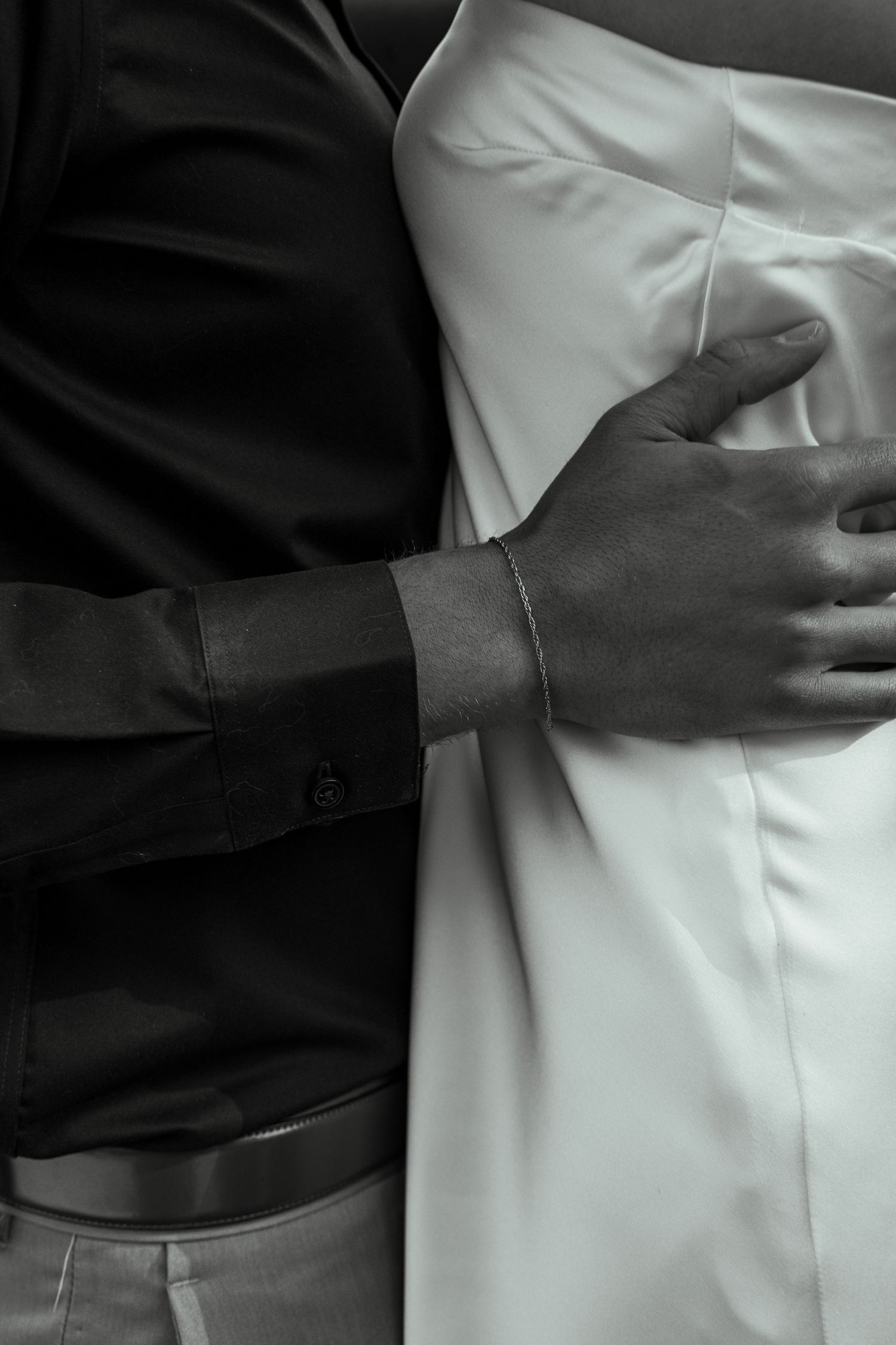 A close-up shot shows hands embracing against white and black formal attire.