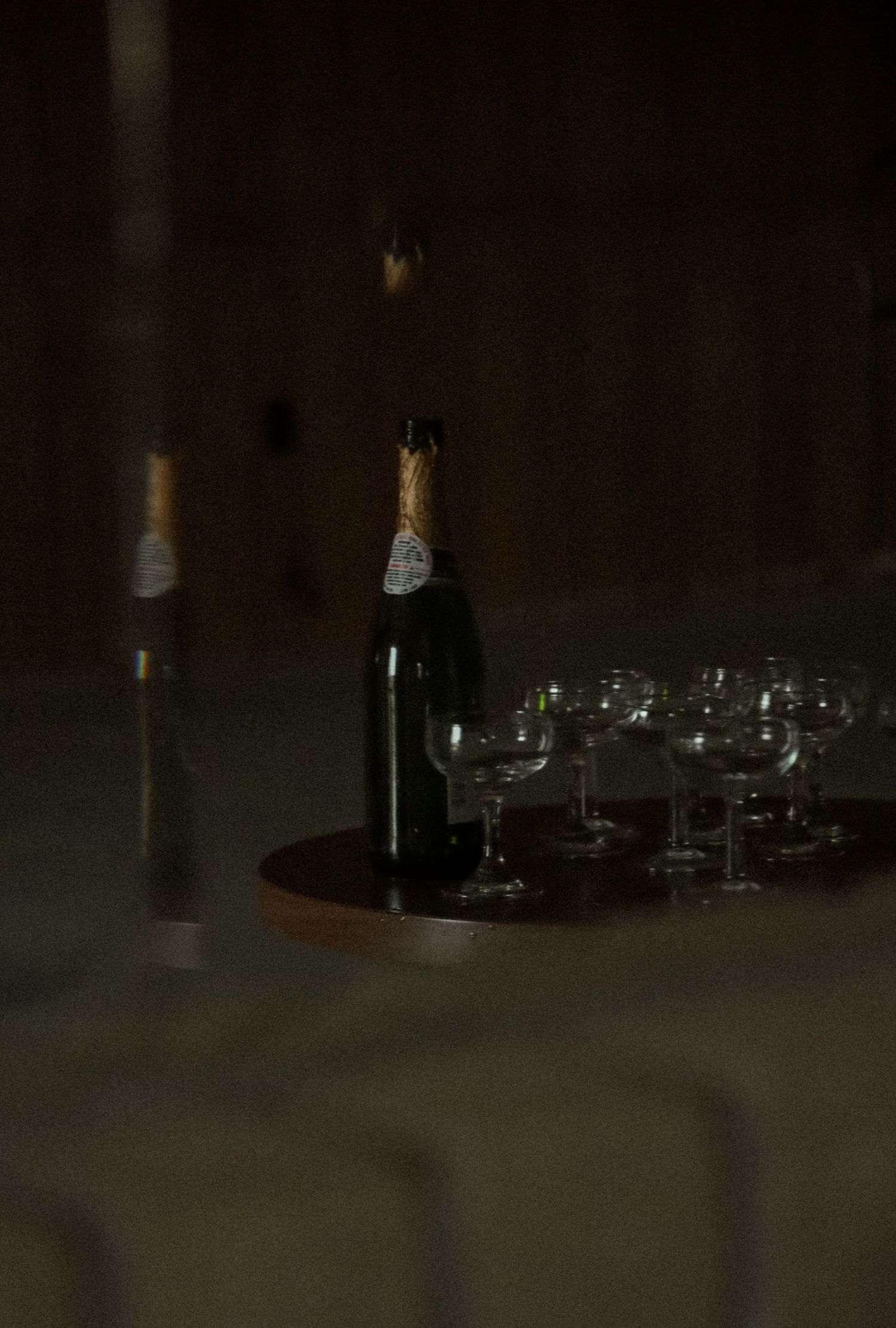 Dark and moody photograph of wine glasses arranged on a table in low light.