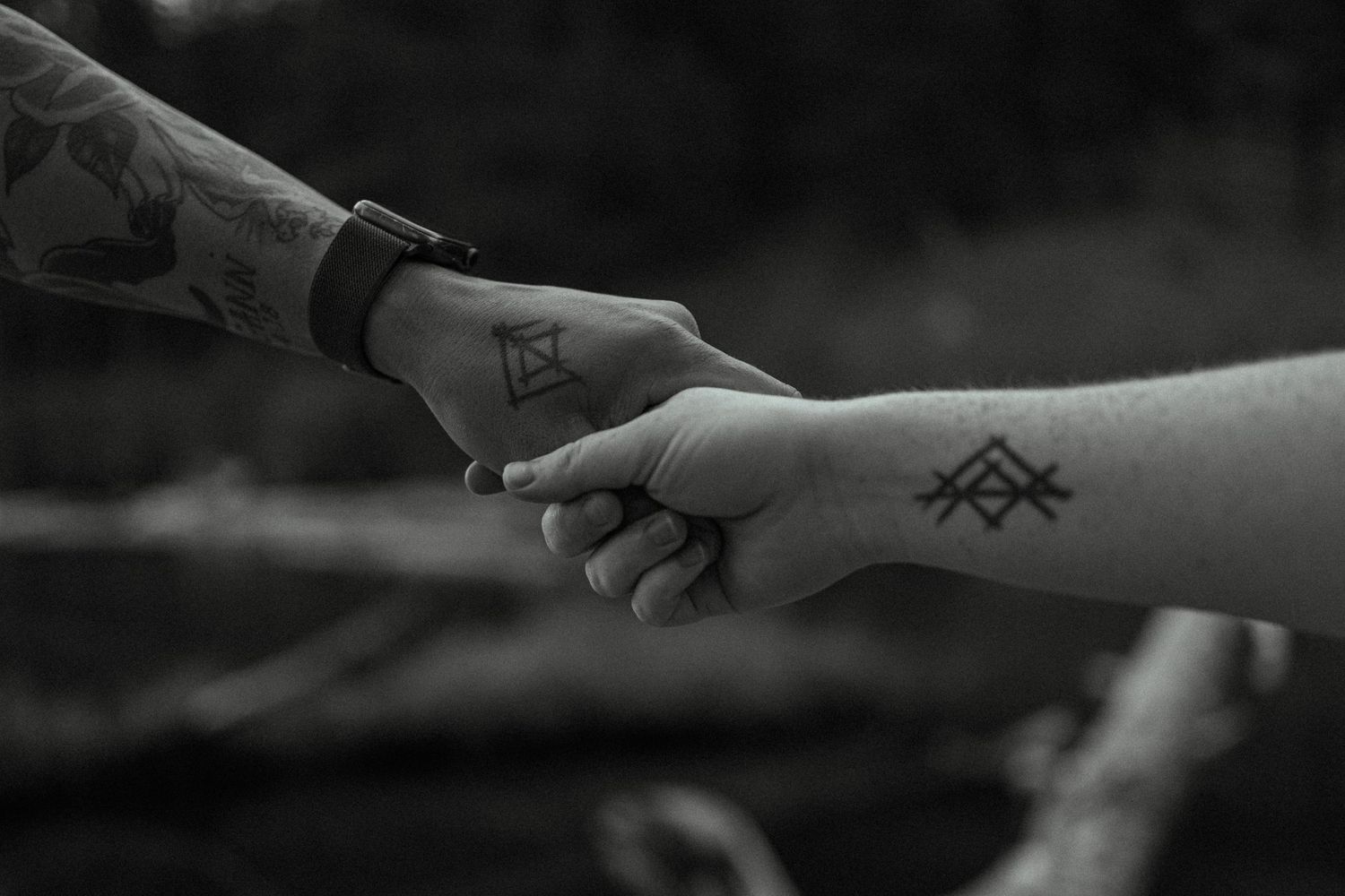 Close-up of hands with minimalist geometric tattoos in black and white.