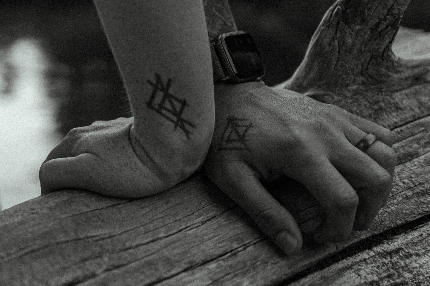 Artistic black and white detail shot of hands with geometric tattoos.