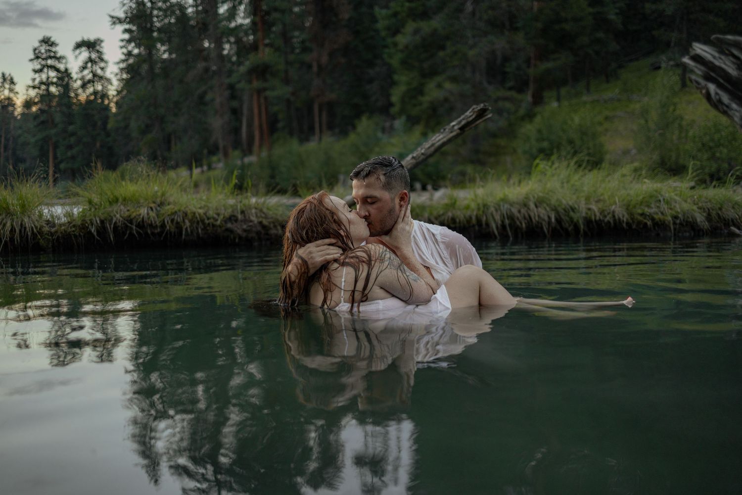 Intimate moment captured of a couple in a peaceful lake at dusk.