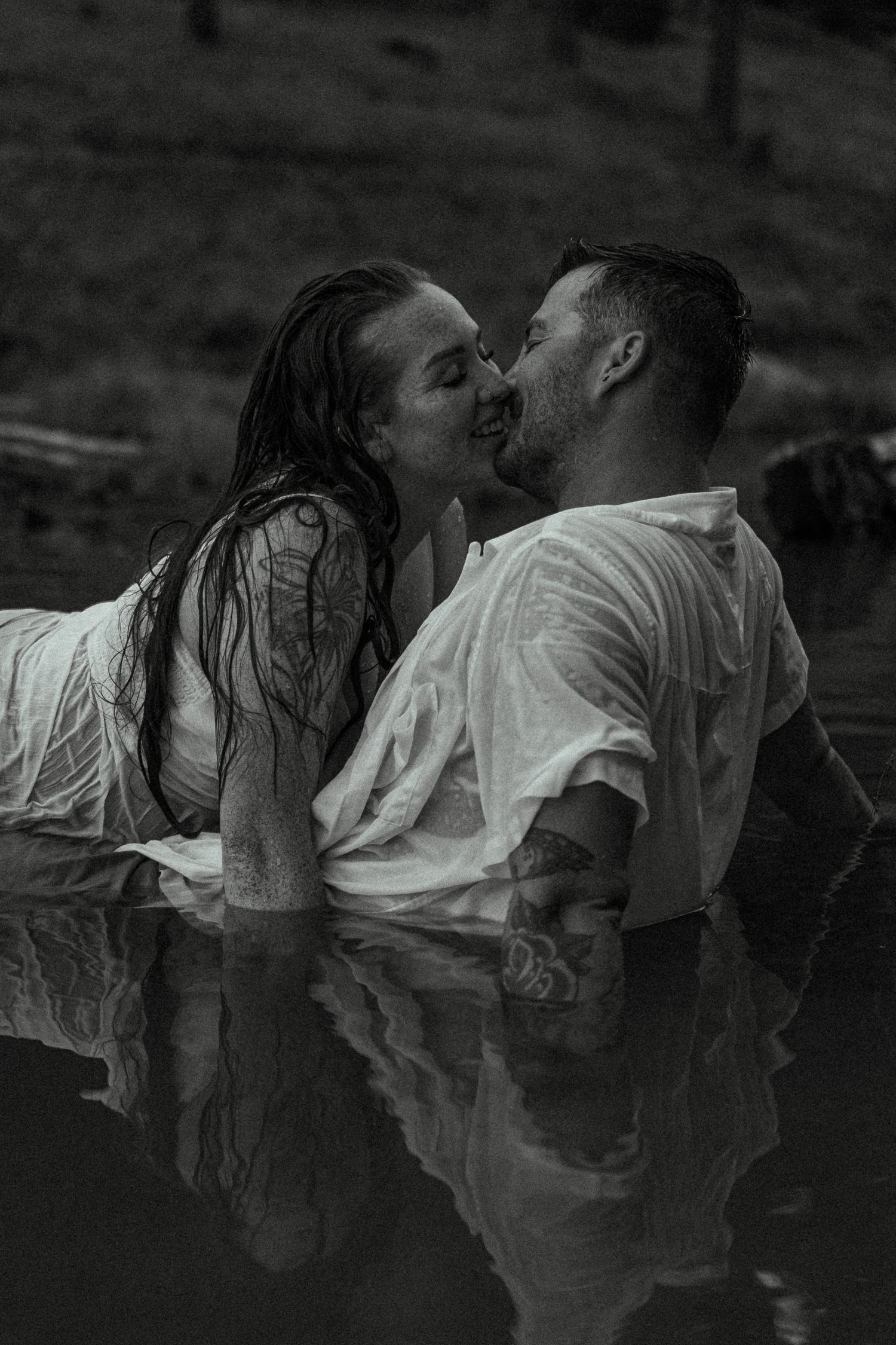 A black and white photo captures a tender moment between a couple in water.