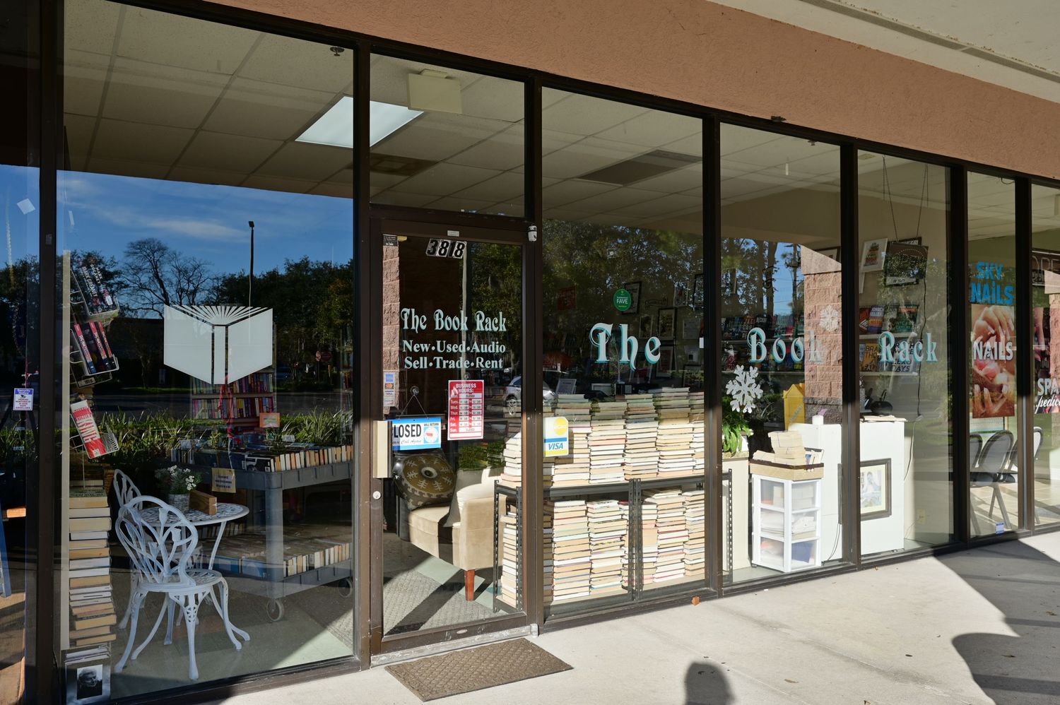 Storefront view of The Book Rack shop with large glass windows and outdoor seating.