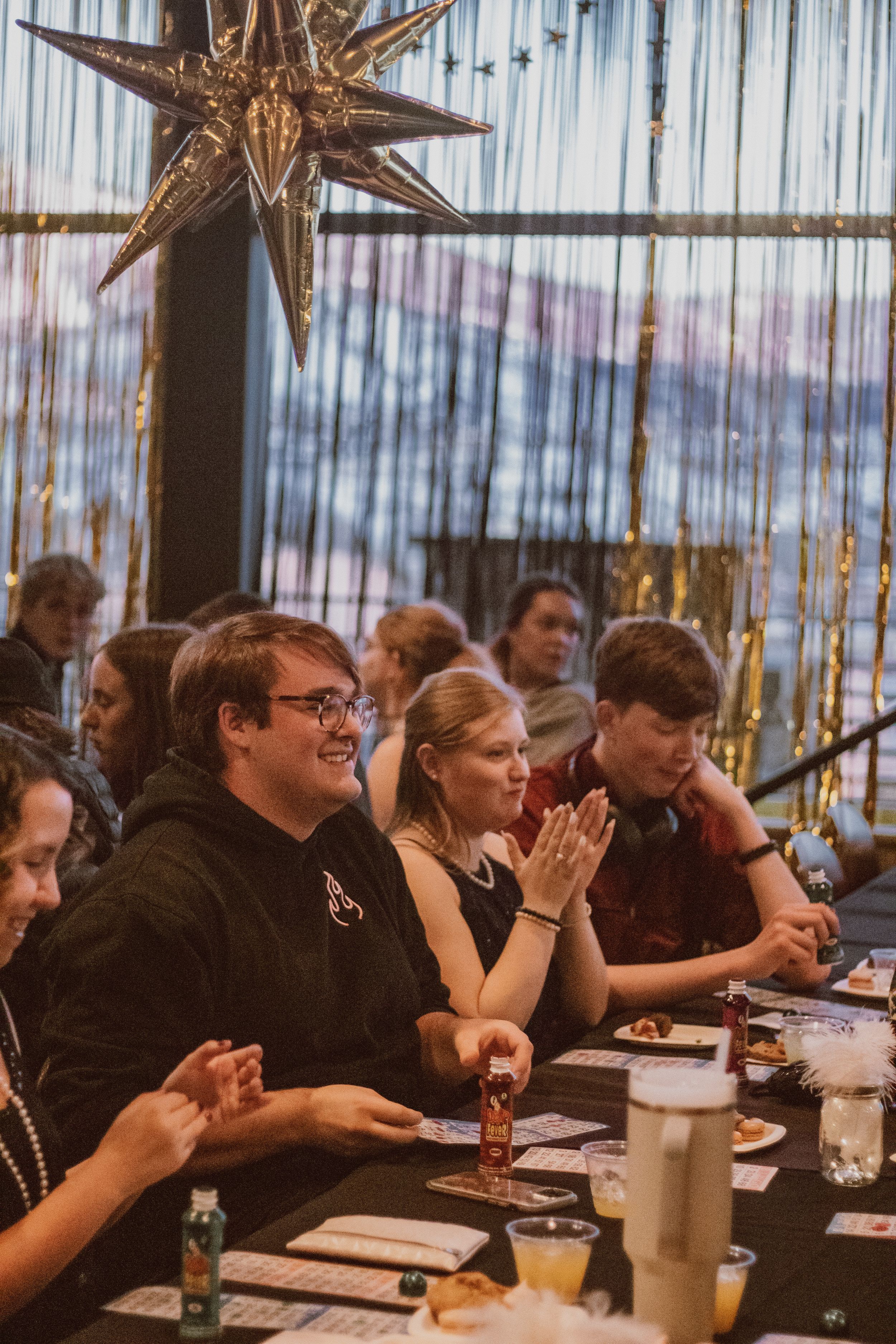 Attendees seated at long tables enjoying a meal under decorative gold stars.