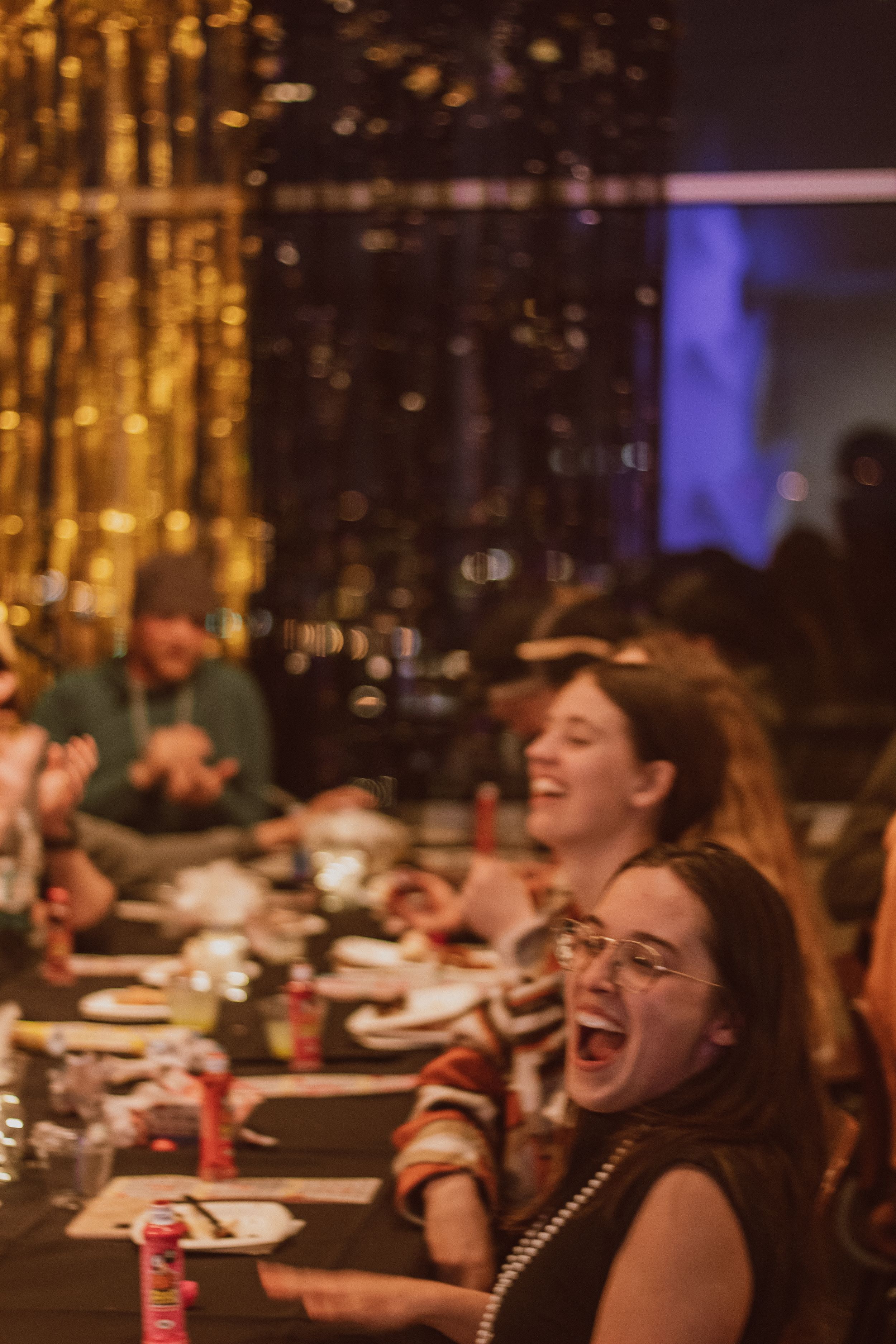 People enjoying a lively dinner gathering under warm lighting and festive decorations.