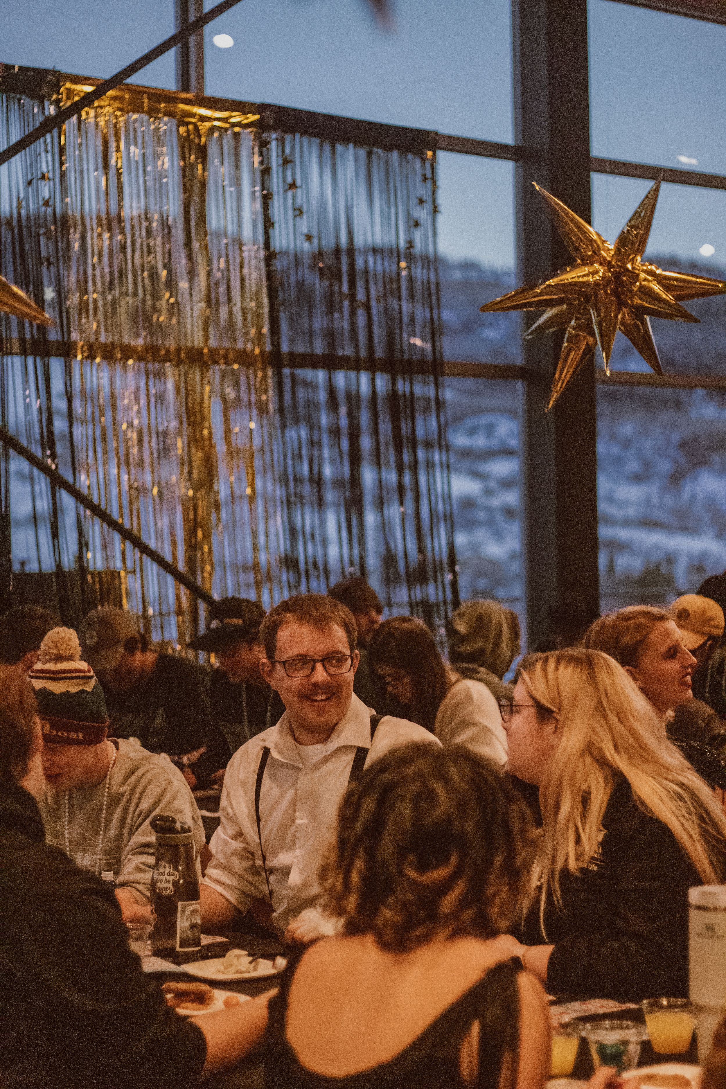 Guests socializing at tables under gold star decorations and string lights.