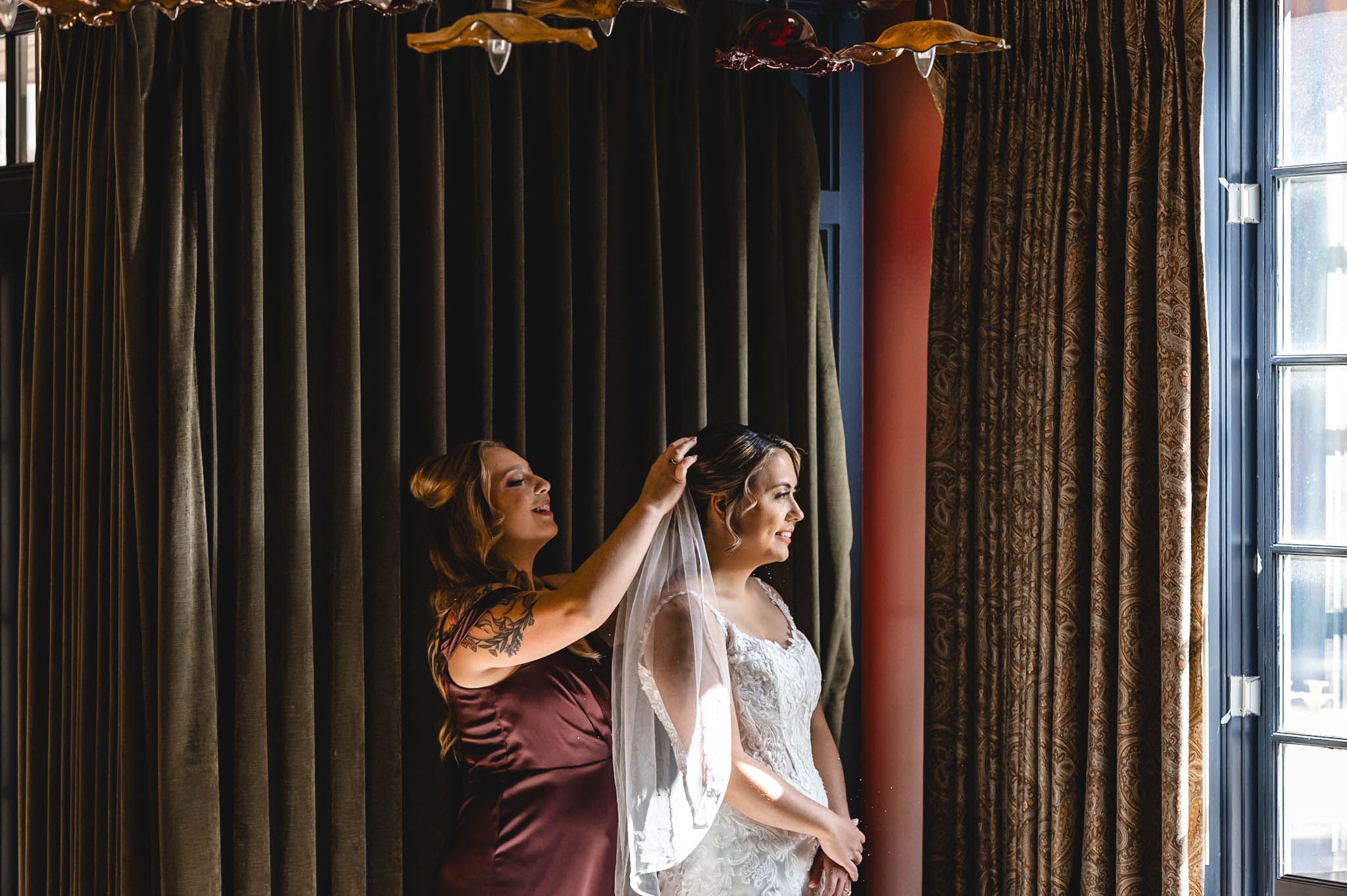 Wedding preparation scene with flowing curtains and natural window light.