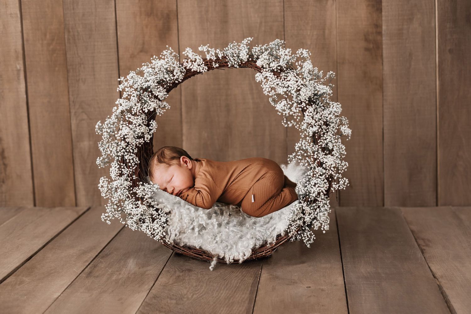 White floral wreath arrangements on wooden backdrop for newborn photography.