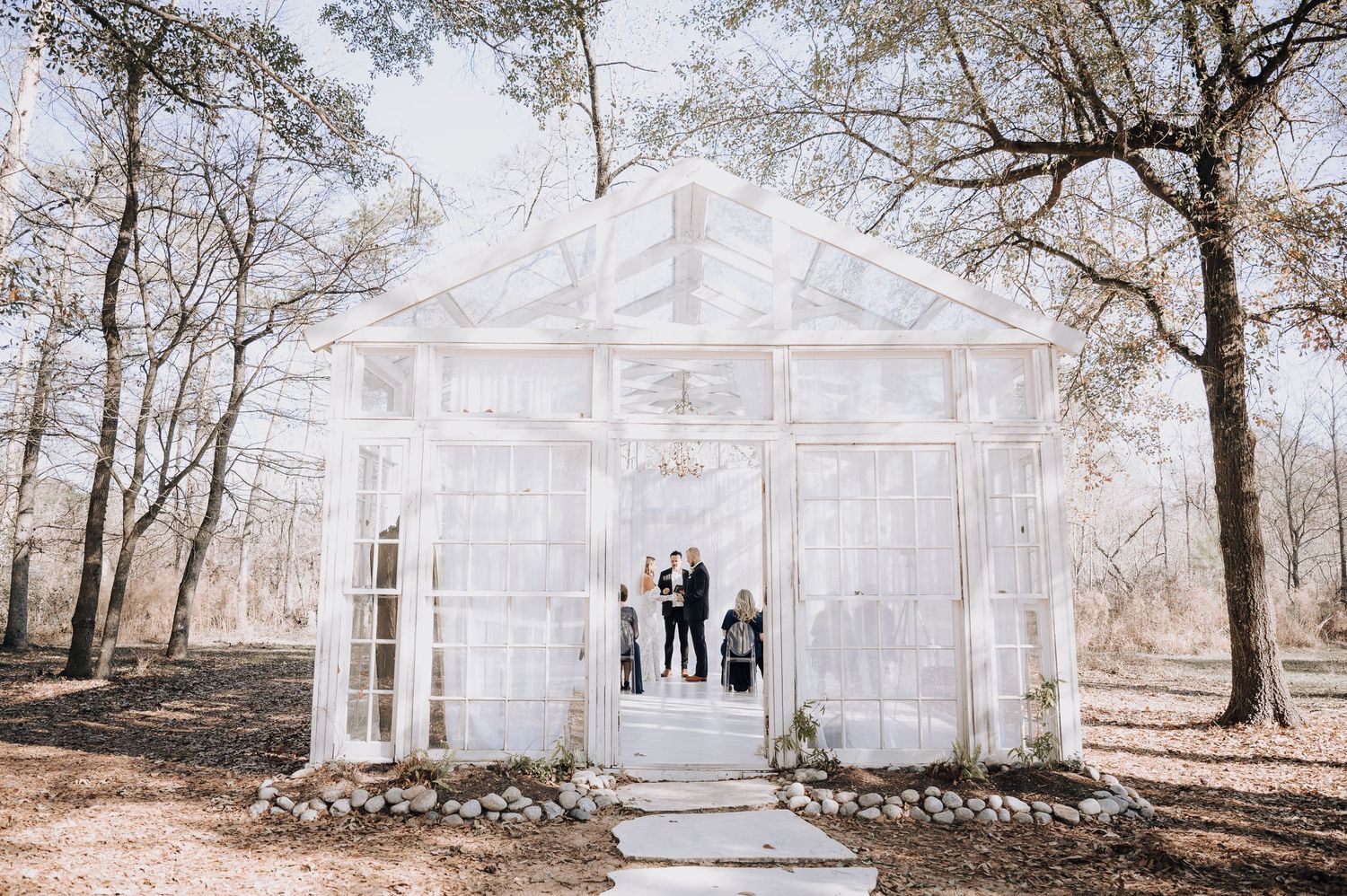 Transparent glass chapel structure in woods creates ethereal wedding ceremony setting.