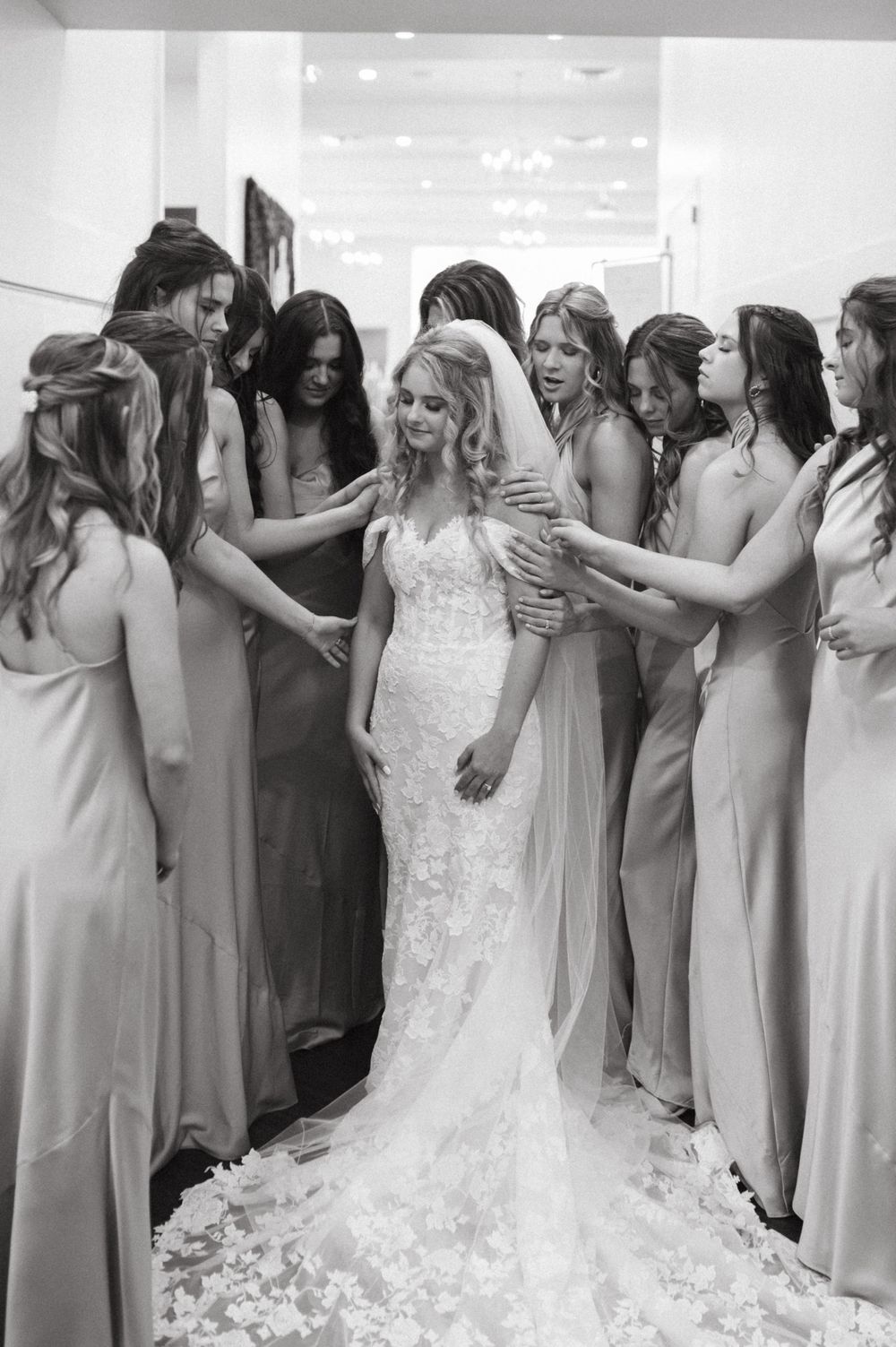 Monochrome image of wedding party gathered around in flowing gowns.