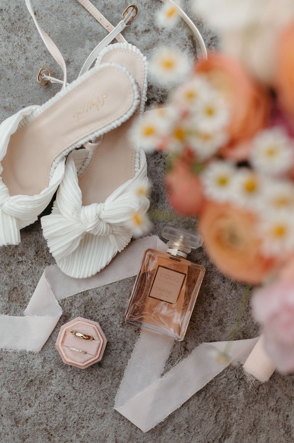 Wedding accessories including white bow heels, perfume bottle and floral details.