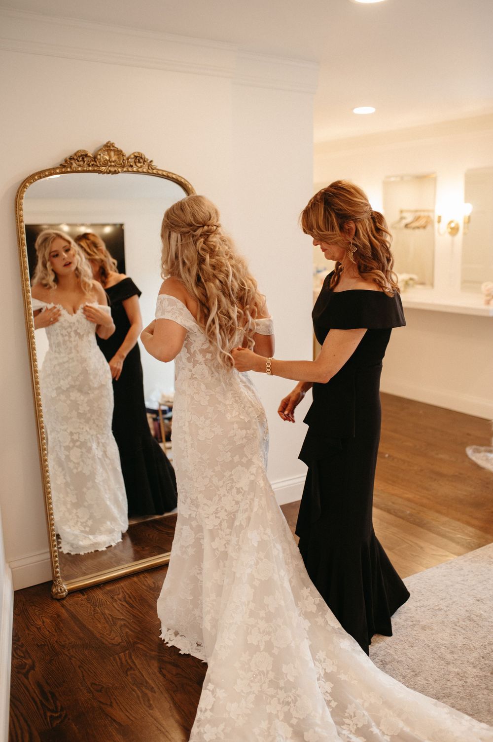 Elegant preparation scene with ornate gold mirror reflecting a wedding dress fitting.