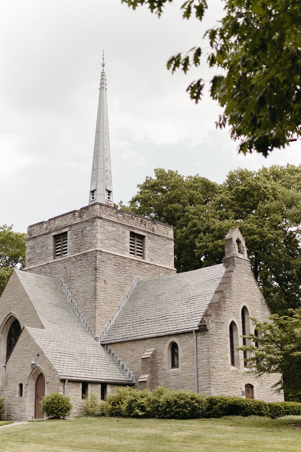 A traditional stone church with a tall spire and Gothic architecture set against an overcast sky.