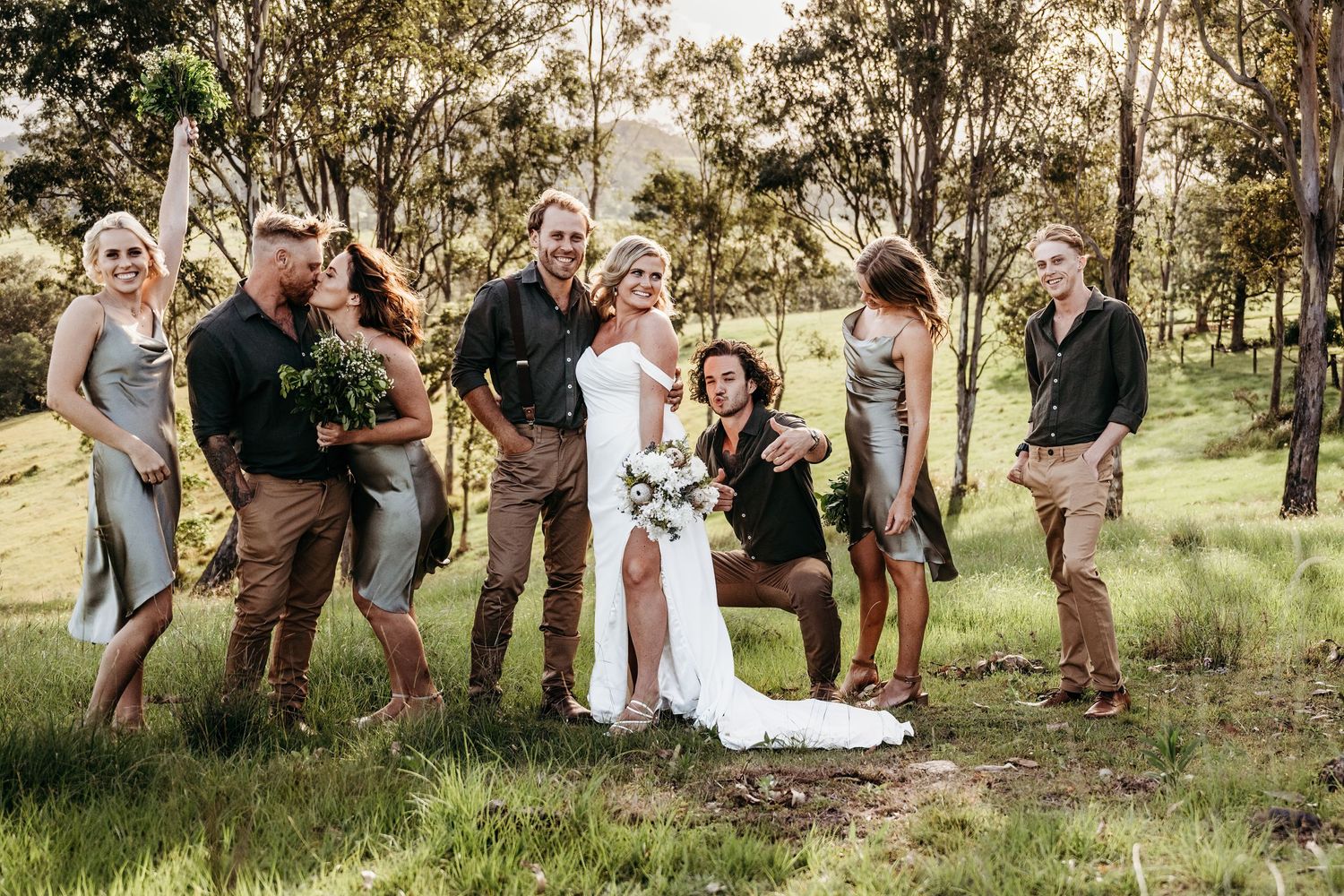 A wedding party poses together in a scenic outdoor setting.