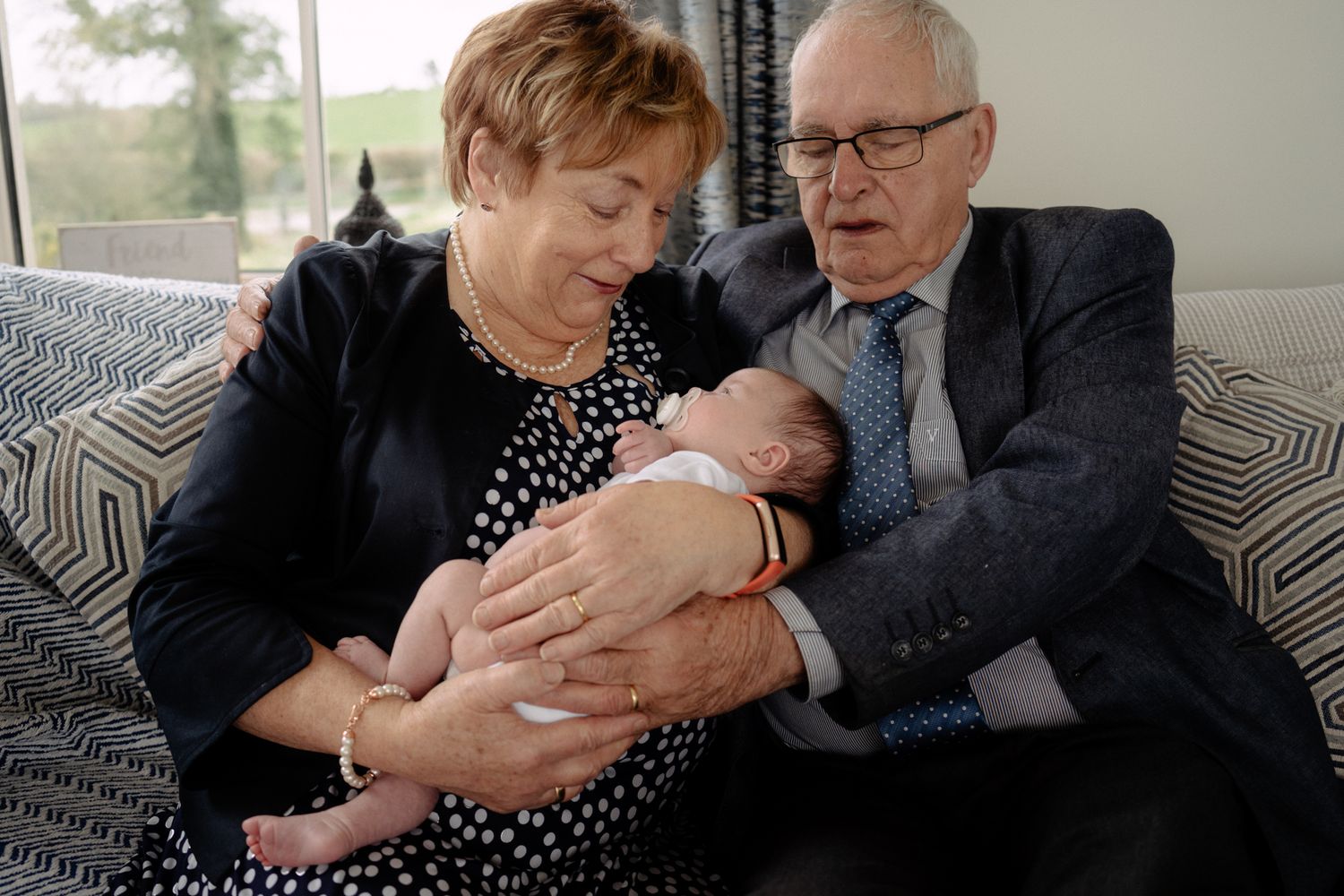 A tender moment showing a baby being cradled by elderly figures on a couch.